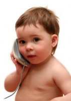Baby playing with computer mouse as if it were a phone. Isolated on white.