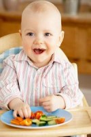 Toddler Enjoying Snack Sitting In High Chair